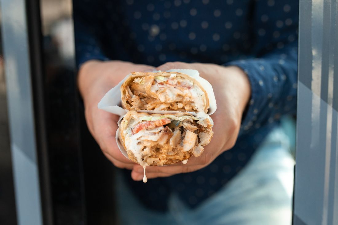 A loaded donair wrap, cut in half and dripping with sweet donair sauce