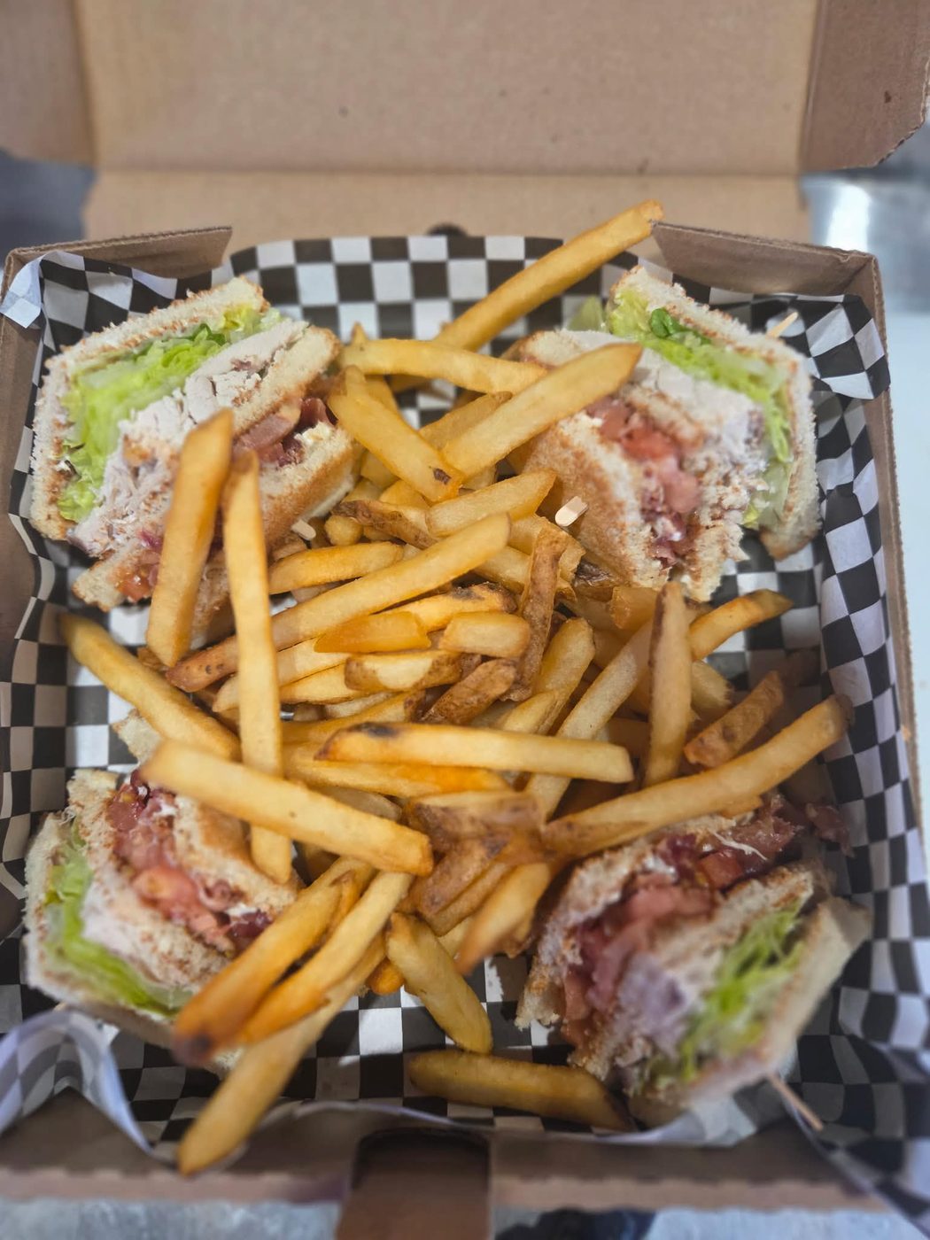 A club house sandwich cut in quarters with a side of fries